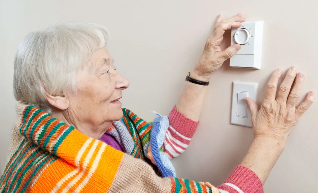 Elderly Woman Turning Up Heating